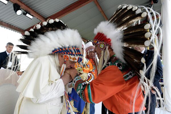 El papa Francisco (izda.) besa la mano de un indígena en Muskwa Park durante su gira por Canadá, donde pidió perdón por los abusos y crímenes cometidos por la Iglesia contra los menores de edad nativos. 25 de julio del 2022. - Sputnik Mundo