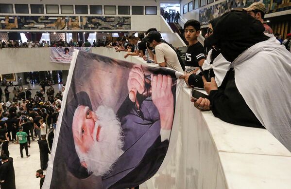 Por su parte, el Ministerio de Defensa iraquí explicó que las tropas gubernamentales habían sido desplegadas en la ciudad para proteger a los manifestantes, la propiedad pública y privada y frustrar los intentos de desestabilización.En la foto: Los partidarios de Muqtada Sadr llevan un retrato del padre de Sadr, el ayatolá Mohammed Sadeq Sadr, en el interior del parlamento iraquí en la Zona Verde de alta seguridad de la capital, Bagdad, el 31 de julio de 2022, un día después de irrumpir en él. - Sputnik Mundo