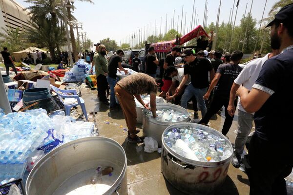 Las protestas en Bagdad comenzaron el 27 de julio. Varios cientos de manifestantes irrumpieron en el edificio del Parlamento, a pesar de los llamamientos del actual primer ministro, Mustafa Kazemi, para que se dispersaran inmediatamente.En la foto: Simpatizantes de Sadr distribuyen agua a otros manifestantes, fuera del parlamento iraquí en la Zona Verde de alta seguridad de la capital, Bagdad, el 31 de julio de 2022. - Sputnik Mundo