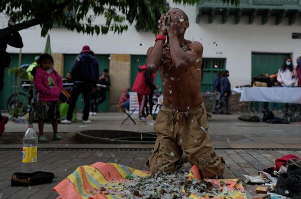 Un artista callejero frota su cara con fragmentos de vidrio en el centro de Bogotá, Colombia. - Sputnik Mundo