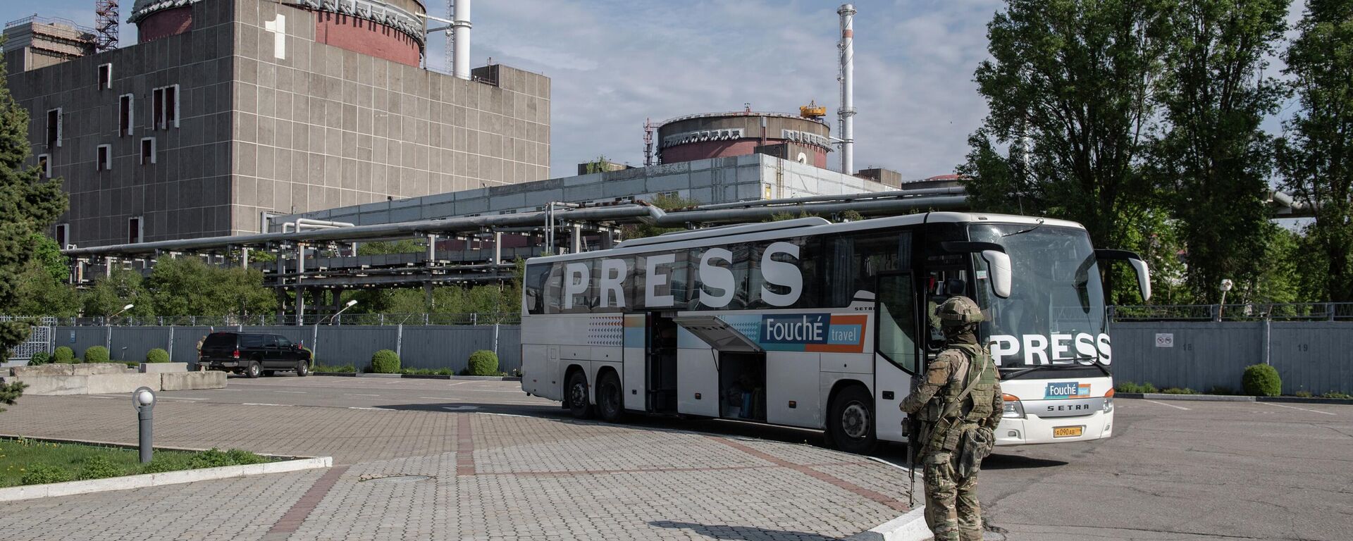 Un soldado ruso y un autobús con prensa internacional en el recinto de la central nuclear de Zaporiyia, en Energodar. - Sputnik Mundo, 1920, 04.09.2022