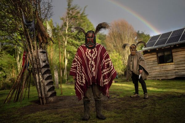 Hombres mapuches posan para una foto con máscaras ceremoniales tradicionales kollón en el pueblo de Carimallin, en el sur de Chile. - Sputnik Mundo