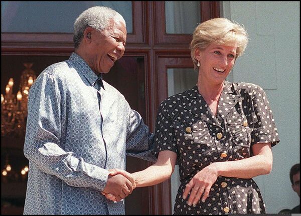 Durante sus años en el palacio real, la princesa de Gales no se volvió fría y reticente en su trato con la gente. Dondequiera que estuviera Lady Di, no escatimaba palabras amables, abrazos y calor humano para nadie; hacía generosas donaciones a organizaciones benéficas, a los refugiados y a las personas sin hogar, y no tenía miedo a entrar en albergues y hospicios.En la foto: la princesa Diana con el presidente sudafricano Nelson Mandela en Ciudad del Cabo, 1997. - Sputnik Mundo