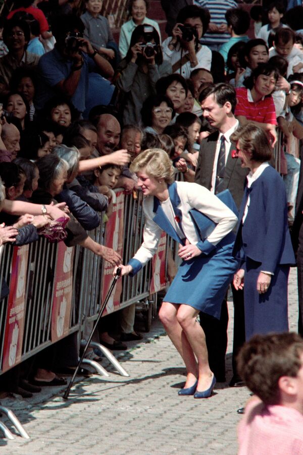 A principios de los años 90, el matrimonio de Diana y Carlos se rompió definitivamente. Incluso se rumoreó que el pelirrojo Harry no era hijo de su esposo y los Windsor supuestamente se sometieron a una prueba de ADN para disipar las dudas. El 9 de diciembre de 1992 se anunció oficialmente en la Cámara de los Comunes la &quot;separación amistosa&quot; de los Príncipes de Gales.En la foto: la princesa Diana devuelve su bastón a una anciana que lo dejó caer durante una visita a Hong Kong, en 1989. - Sputnik Mundo