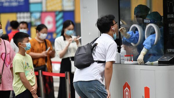 Un trabajador sanitario toma una muestra de hisopo de un hombre para la prueba del COVID-19 en la ciudad de Chengdu - Sputnik Mundo