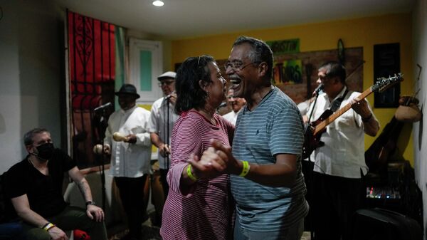 Una pareja baila al ritmo de la música de un grupo local conocido como 'Son Mondondo' en Caracas, Venezuela - Sputnik Mundo