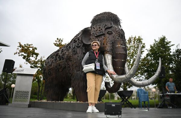 Una mujer se hace una foto con una escultura de un mamut. - Sputnik Mundo