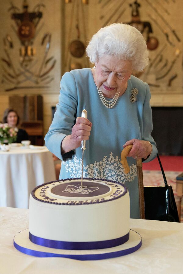 Pero, a pesar de todo, Isabel supo hacer que la Corona británica siguiera siendo un símbolo de respeto y estabilidad. En la foto: Isabel II corta la tarta durante las celebraciones del Jubileo de Platino en su residencia de Norfolk, Inglaterra, 2022. - Sputnik Mundo