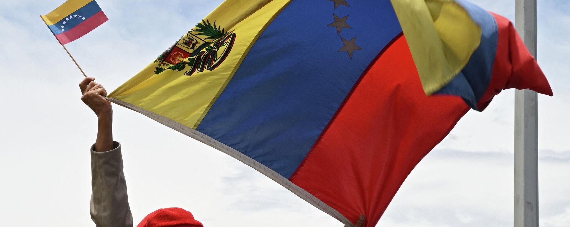 Un hombre levanta la bandera de Venezuela en la ceremonia de reapertura de la frontera con Colombia - Sputnik Mundo, 1920, 26.09.2022