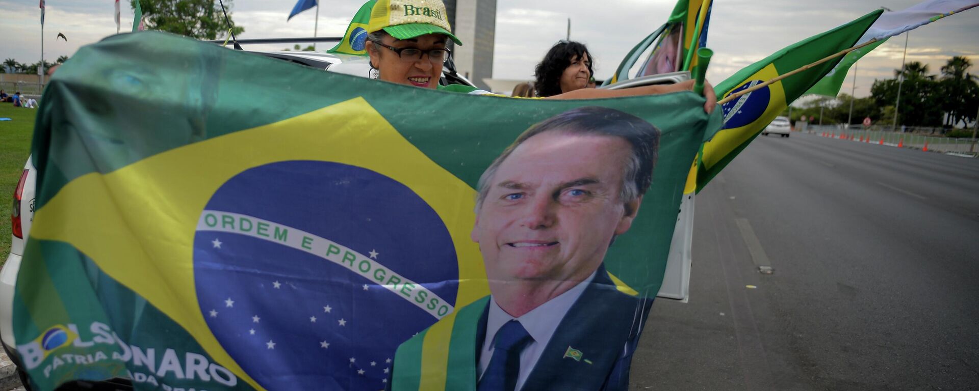Una mujer sostiene una bandera con la imagen del presidente de Brasil, Jair Bolsonaro en las elecciones presidenciales - Sputnik Mundo, 1920, 14.10.2022