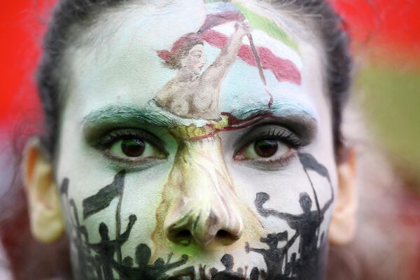 Una de las mujeres que participó durante una protesta en París tras la muerte en Teherán de la joven de 22 años Mahsa Amini, quien fue detenida por la policía iraní por tener mal colocado su hiyab. La manifestante en la fotografía lleva pintada en el rostro a Marianne, un símbolo de la República Francesa. - Sputnik Mundo
