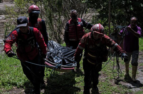 Los socorristas transportan el cuerpo de un fallecido recuperado de debajo de un desprendimiento de tierra a orillas del río Tuy. - Sputnik Mundo