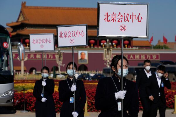 Unas guías de autobús sostienen unos carteles para orientar a los delegados después de la clausura del XX Congreso Nacional del Partido Comunista de China, en Pekín.  - Sputnik Mundo