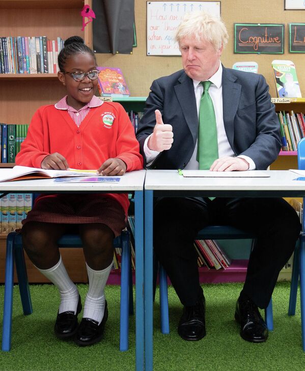 El ex primer ministro británico, Boris Johnson, hace un gesto con su pulgar hacia arriba durante su visita a unos estudiantes de la escuela primaria de Santa María Cray, en el sureste de Londres. 23 de mayo de 2022. - Sputnik Mundo
