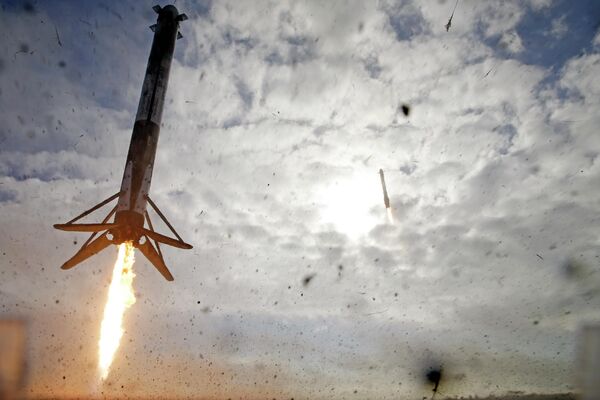 Los dos propulsores laterales de un cohete SpaceX Falcon Heavy, a la izquierda y en la parte trasera del centro, regresan a Cabo Cañaveral (EEUU) para aterrizar unos ocho minutos después del despegue. - Sputnik Mundo