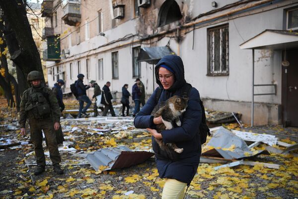Una mujer con un gato cerca de un edificio residencial dañado por los bombardeos ucranianos en Donetsk. - Sputnik Mundo
