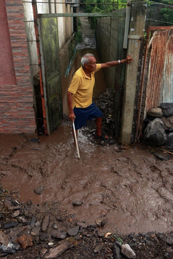 El desprendimiento de tierra destruyó más de 10 casas y otras 60 corren riesgo de derrumbarse. En la foto, un residente de Puerto La Cruz inspecciona su domicilio dañado por el deslave. - Sputnik Mundo