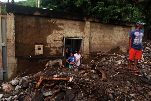 Residentes permanecen entre los escombros de las casas destruidas tras las fuertes lluvias en el sector Valle Verde de Puerto La Cruz, ocurridas el 4 de noviembre de 2022. - Sputnik Mundo