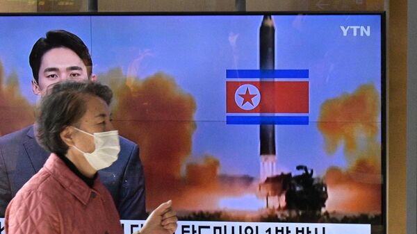Una mujer camina frente a un televisor durante una transmisión de una prueba con misiles de Corea del Norte, el 17 de noviembre de 2022 - Sputnik Mundo
