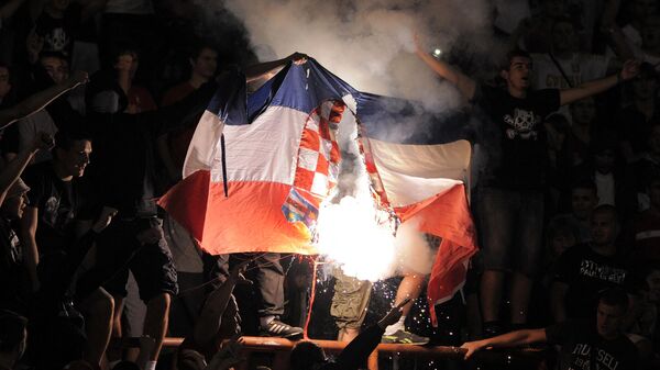 Un grupo de aficionados ultras de Serbia quema una bandera croata durante un partido clasificatorio para el Mundial de Brasil de 2014, en Belgrado - Sputnik Mundo