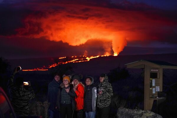 Unas personas posan delante de la lava expulsada por el volcán Mauna Loa, en Hawai. - Sputnik Mundo
