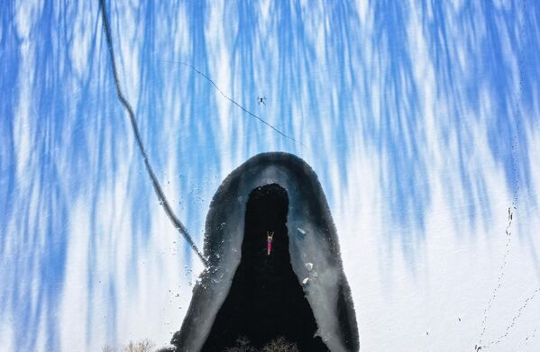 Una imagen aérea de un nadador en un lago parcialmente helado tras una nevada en Shenyang, provincia china de Liaoning. - Sputnik Mundo