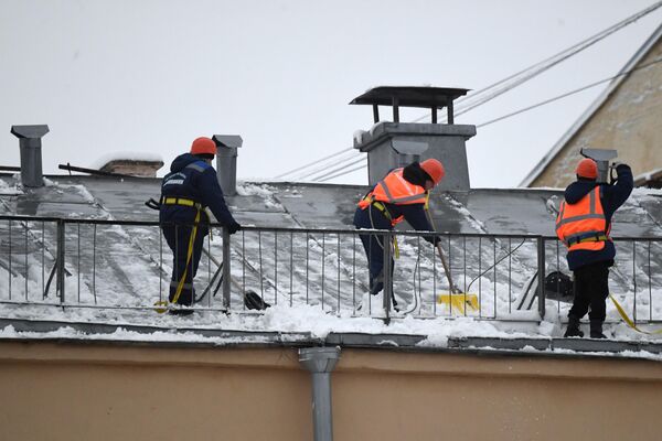 Tres trabajadores recogen la nieve de los tejados. - Sputnik Mundo