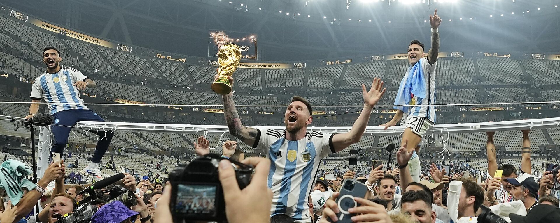 El argentino Lionel Messi celebra con el trofeo ante los aficionados tras ganar la final del Mundial de fútbol entre Argentina y Francia, 18 de diciembre de 2022. - Sputnik Mundo, 1920, 04.10.2023