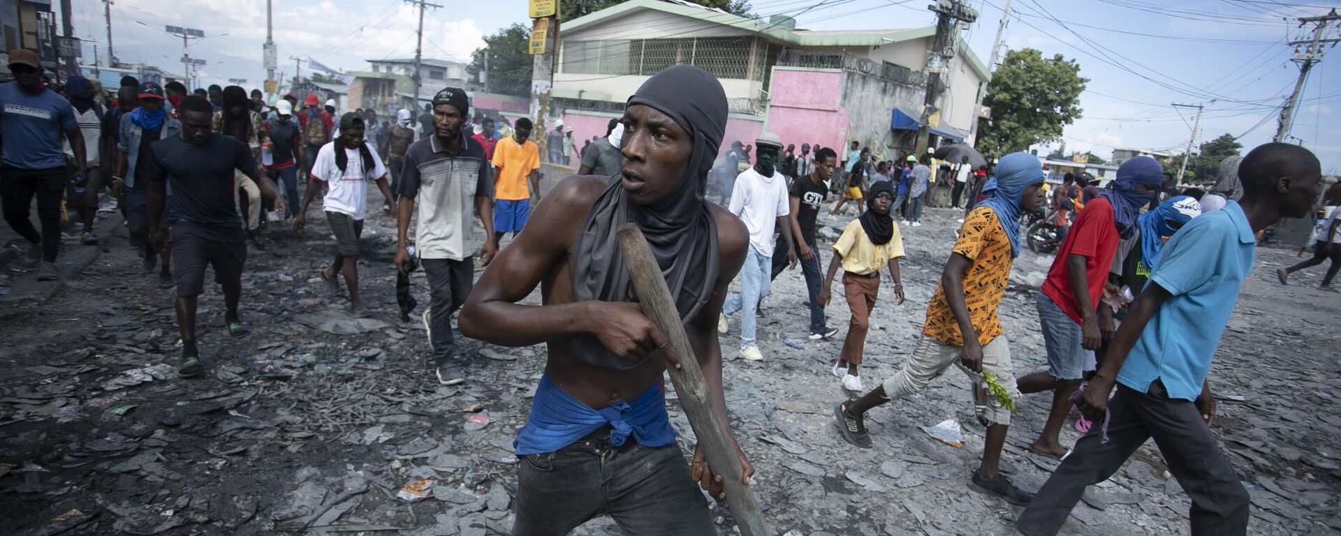Un manifestante en Haití porta un trozo de madera que simula un arma durante una protesta que exige la dimisión del primer ministro, Ariel Henry - Sputnik Mundo, 1920, 26.12.2022