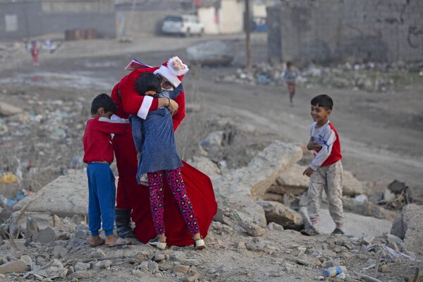 Mohamed Maarouf, residente de Basora (Irak) vestido de Papá Noel, reparte regalos a los niños que viven en un barrio marginal. - Sputnik Mundo