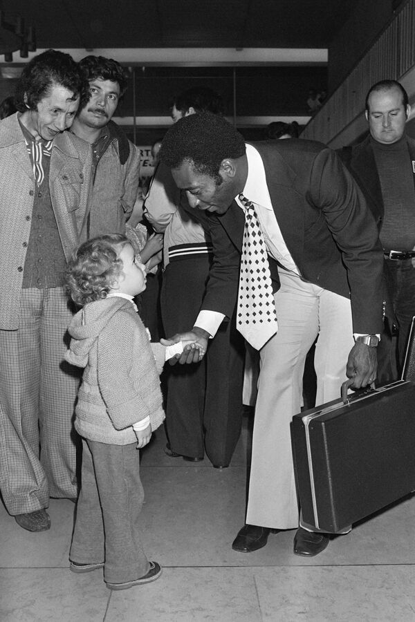 A los 15 años, el astro sudamericano fue invitado a uno de los clubes más fuertes de Brasil, el Santos (Sao Paulo), en cuya plantilla (1956-1974) se convirtió en bicampeón de la Copa Intercontinental (1962, 1963) y de la Copa Libertadores (1962, 1963), seis veces campeón de Brasil, diez veces campeón del estado de Sao Paulo y ganador de muchas otras competiciones.En la foto: Pelé saluda a su hijo en el aeropuerto de Orly, en París, en 1976. - Sputnik Mundo