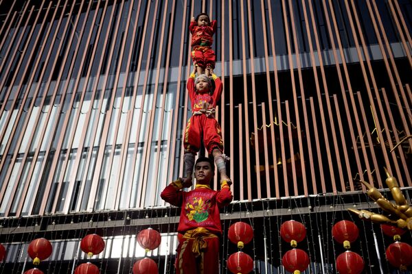 Jóvenes acróbatas forman una torre humana durante una actuación en vísperas del Año Nuevo Lunar en el barrio chino de Bangkok. - Sputnik Mundo