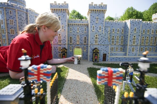 Una empleada de Legoland en Windsor, el Reino Unido, instala figuras del príncipe Harry y su prometida, la actriz estadounidense Meghan Markle, en el castillo de Windsor en vísperas de su boda. - Sputnik Mundo