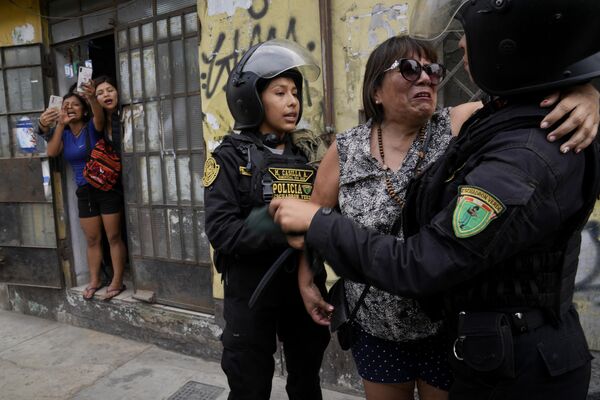 Agentes de policía calman a una mujer que estaba siendo acosada por los manifestantes antigubernamentales frente a la Universidad de San Marcos en la capital peruana de Lima. - Sputnik Mundo