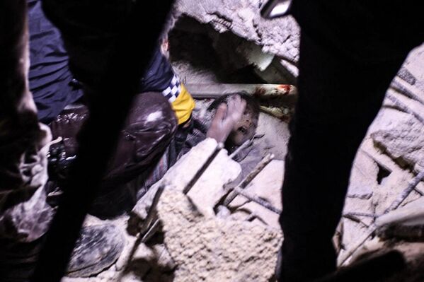 Los rescatistas intentan sacar a un niño de los escombros de un edificio derrumbado en la ciudad fronteriza siria de Azaz, en el norte de la provincia de Alepo. - Sputnik Mundo