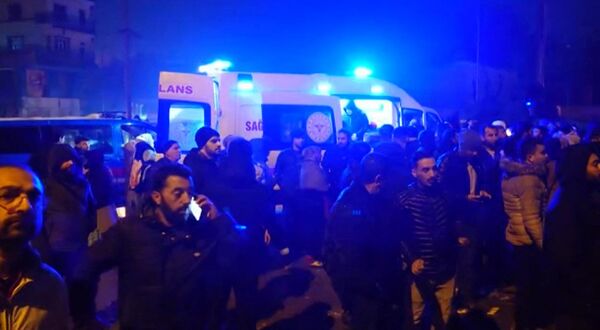 Varias personas permanecen junto a una ambulancia mientras los equipos de rescate buscan a las víctimas del terremoto en Diyarbakir, Turquía. - Sputnik Mundo