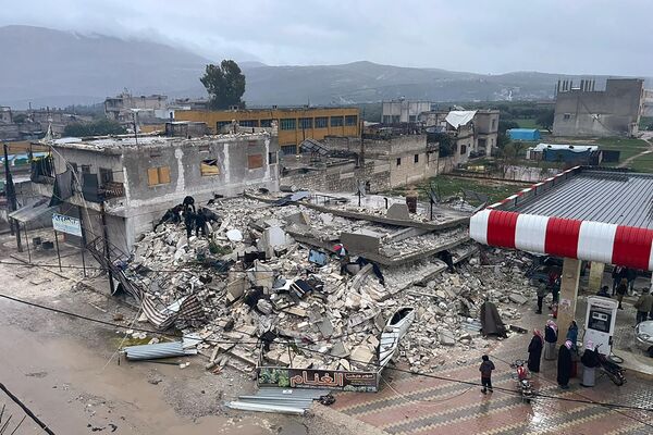 Varias personas entre los escombros de un edificio derrumbado en la ciudad de Azmarin, en la provincia de Idlib, en el norte de Siria. - Sputnik Mundo