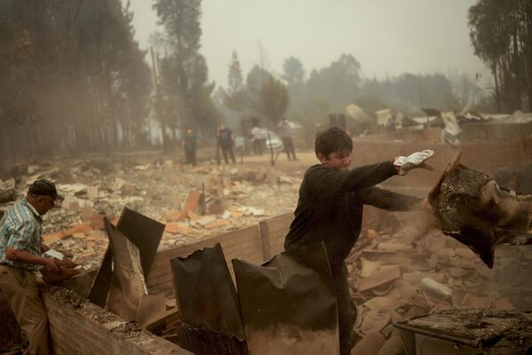 Los incendios forestales en el sur de Chile destruyeron más de 800 viviendas.En la foto: así retiran los escombros de una casa incendiada en Tome. - Sputnik Mundo