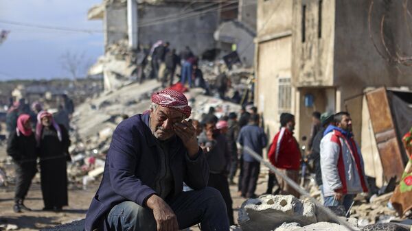 Un hombre sirio llora sentado sobre los escombros de un edificio derrumbado en la ciudad de Jindayris, controlada por los rebeldes, el 7 de febrero de 2023, tras un terremoto mortal.  - Sputnik Mundo