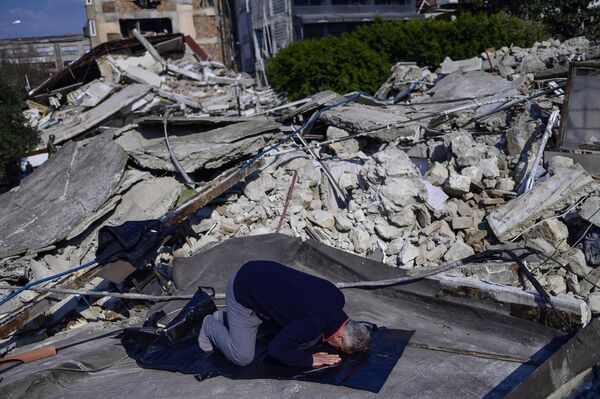 Un hombre reza en el lugar destruido de la gran mezquita de Antakya. - Sputnik Mundo