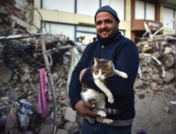 Un residente de Kahramanmaras con su gato rescatado de debajo de los escombros de un edificio derrumbado. - Sputnik Mundo