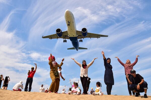 Turistas se fotografían en la playa de Mai Khao frente a un avión que se prepara para aterrizar en el aeropuerto de Phuket, Tailandia. - Sputnik Mundo