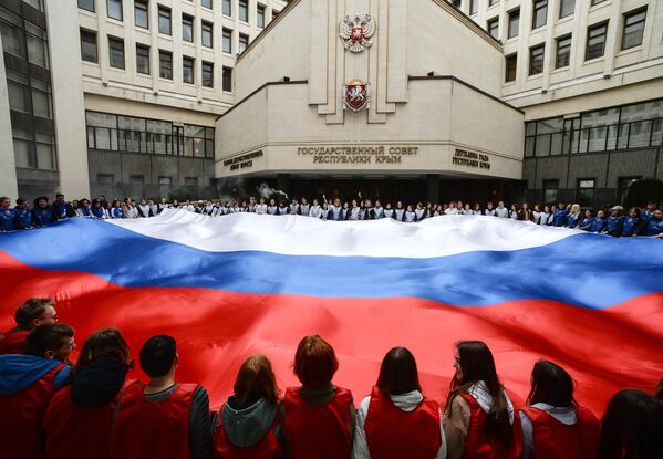 Activistas despliegan una enorme bandera rusa frente al Parlamento de Crimea con motivo del Día de la Reunificación de Crimea con Rusia. - Sputnik Mundo