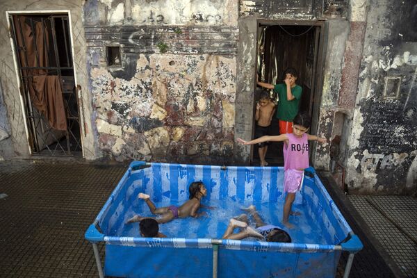 Niños juegan en una piscina en la vereda del barrio de La Boca en Buenos Aires, Argentina. El país está viviendo desde hace unos días un verano anormalmente caluroso con temperaturas que superan constantemente los 40 °C. - Sputnik Mundo