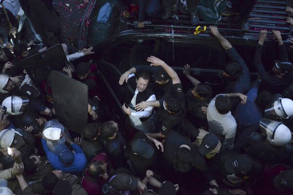 Personal de seguridad se abre paso entre la multitud frente al tribunal de Lahore, Pakistán, ante la llegada del ex primer ministro del país Imran Jan para una vista judicial. - Sputnik Mundo