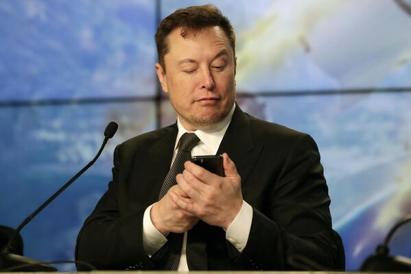 El director general de SpaceX, Elon Musk, en una conferencia de prensa posterior al lanzamiento de prueba de Falcon 9, finge estar buscando una respuesta a la pregunta de un periodista en internet, 2020. - Sputnik Mundo
