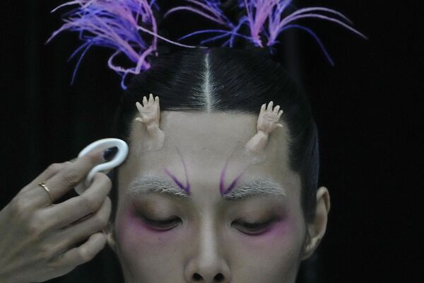 Una modelo de las colecciones del diseñador chino Dong Yaer se maquilla durante la Semana de la Moda de China en Pekín. - Sputnik Mundo