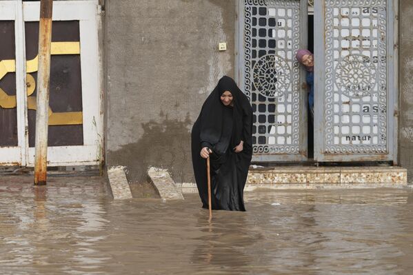 Una mujer deambula por una calle inundada tras las fuertes lluvias en el santuario central iraquí de Nayaf. - Sputnik Mundo