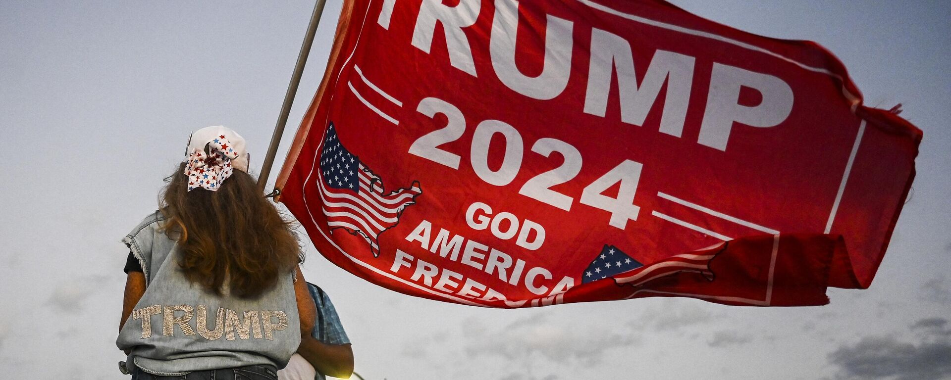 Una partidaria del expresidente estadounidense Donald Trump sostiene una bandera de 'Trump 2024' mientras protesta cerca del club Mar-a-Lago en Palm Beach, Florida, el 30 de marzo de 2023.  - Sputnik Mundo, 1920, 02.04.2023