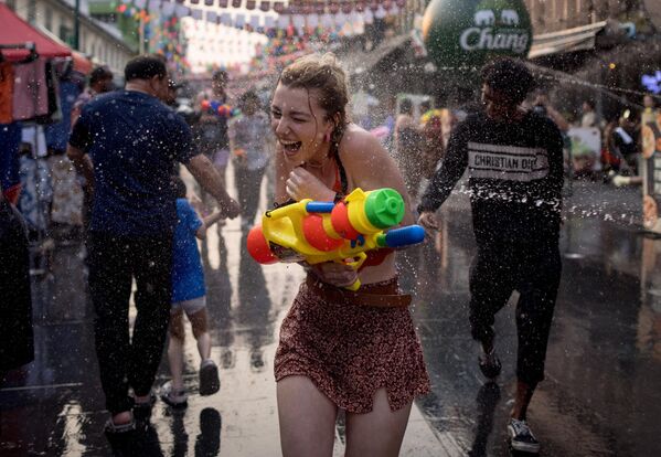 Una joven empapada corre por una calle de Bangkok, donde los lugareños organizaron una pelea de agua en vísperas del Songkran, el Año Nuevo tailandés. - Sputnik Mundo